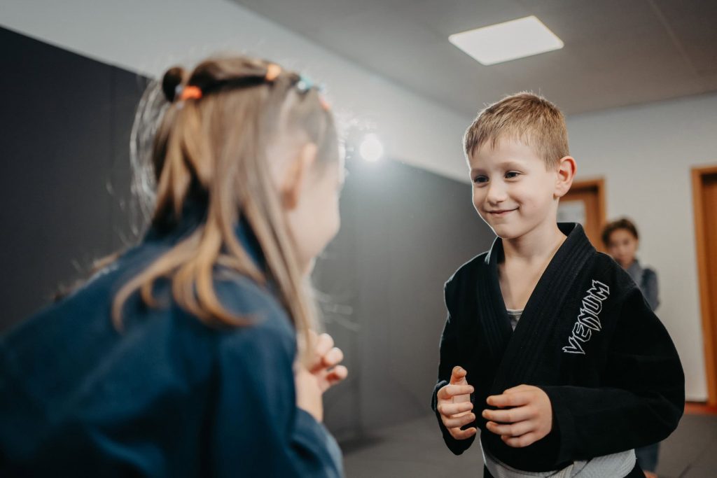 Kinder beim Luta Livre Training, konzentriert und lachend während einer Partnerübung im Trainingsraum.
