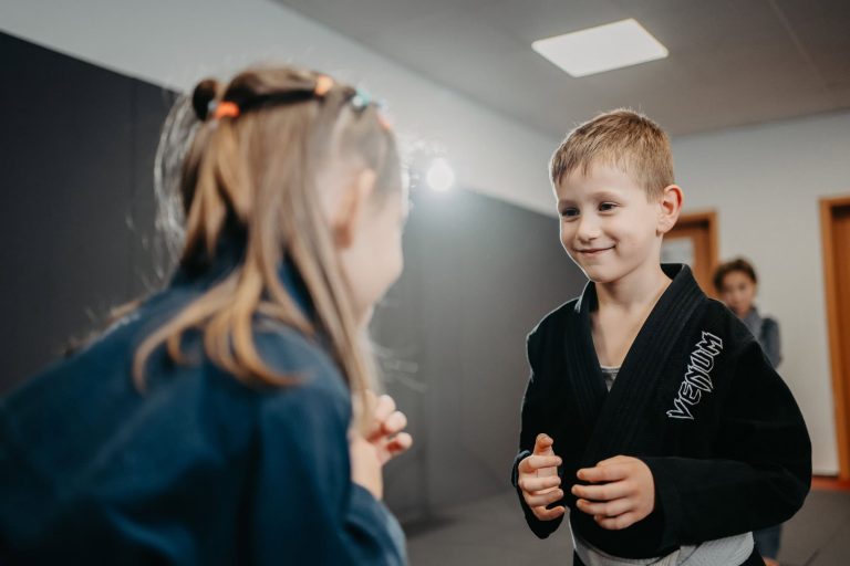Über uns 18 Kinder beim Luta Livre Training, konzentriert und lachend während einer Partnerübung im Trainingsraum.