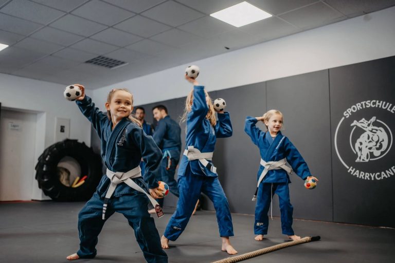 Über uns 7 Kinder im blauen Gi bei spielerischen Übungen mit Bällen im Kindertraining bei Harrycane Luta Livre.