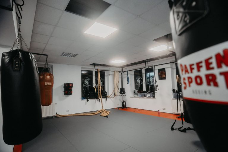 Über uns 8 Trainingsraum der Sportschule Harrycane mit Boxsäcken, Kletterseilen und gepolsterter Matte, bereit für intensives Training.
